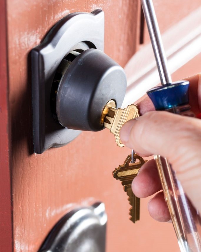 locksmith-inserting-a-golden-key-to-a-deadbolt-lock-of-the-front-door